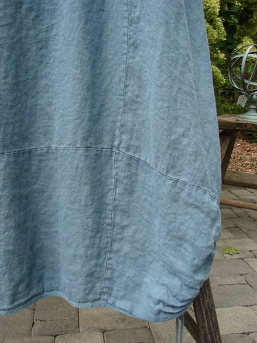 Barclay Linen Lucky Urchin Dress Floral Drift Delaware size 2 in washed blue linen, shown in a close-up of the flowing hem with visible seam lines, soft wrinkles, and a lightly curved edge.