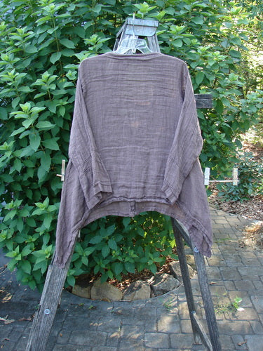 Barclay Linen Deep V Neck Three Button Top Unpainted Peat Size 0 displayed on a wooden rack, showcasing its lightweight linen fabric, three-quarter pinched sleeves, and distinctive varying dippy hemline.