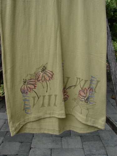 1998 Botanicals Calla Dress Echinacea Seed Size 0 in muted olive green, shown in a close view of the hem with soft, lightweight fabric and a gently draped, layered edge. Floral calla and echinacea prints, along with faded botanical lettering, sit across the lower front in subdued pink, blue, and brown tones.
