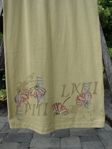 1998 Botanicals Calla Dress Echinacea Seed Size 0 in muted olive fabric, with a long straight drape and a hemline decorated by layered floral and striped calla-style motifs in faded pink, blue, and brown. The soft textile hangs against an outdoor stone path and greenery, emphasizing its light, airy finish.