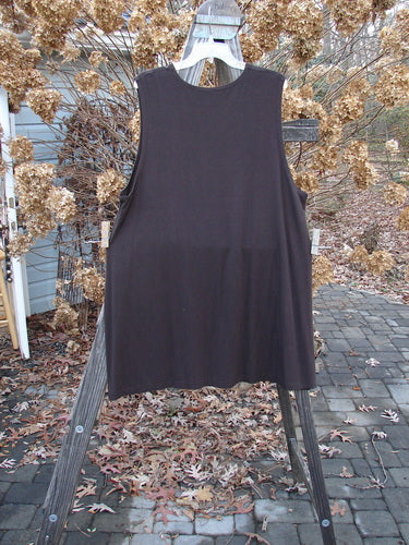 A Barclay Rayon Lycra A Line Tunic in Mortar, size 2, displayed on a wooden rack. Features include a rounded neckline, deeper arm openings, and a widening lower shape. The tunic has a superior bounce and sway, made from a stretchy and forgiving fabric.