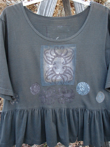 1992 Holiday Short Sleeved Peplum Top Black Sand Size 1: A grey shirt with a design on it, featuring a close-up of a tattoo and a close-up of a striped shirt.