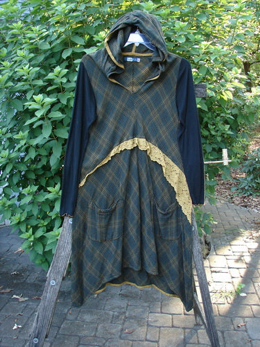Barclay Rayon Linen Ruffle Pocket Dress in Brown Plaid, featuring a hi-low hemline, ribbed sleeves, contrasting gold piping, and lace accents, displayed on a clothes rack.