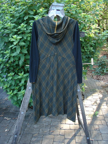 Barclay Rayon Linen Ruffle Pocket Dress in Brown Plaid displayed on a wooden rack, highlighting its hi-low hemline, contrasting lace accents, and long ribbed sleeves, embodying BlueFishFinder's vintage, creative style.