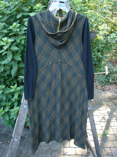 Barclay Rayon Linen Ruffle Pocket Dress in Brown Plaid, featuring a hi-low hemline, gold piping, lace accents, and long ribbed sleeves, showcased in a close-up emphasizing its detailed design.