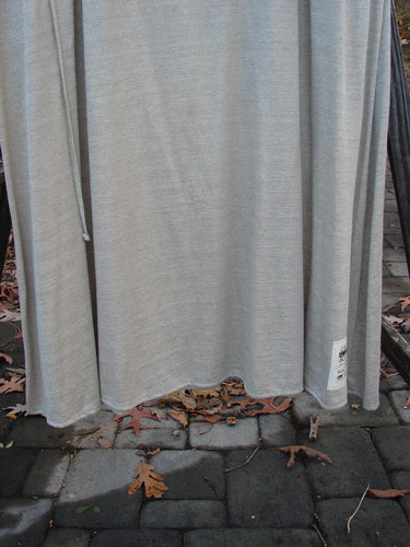 1998 Linen Knit Wrap Dress Unpainted Natural Size 2: A grey fabric shirt with a stone on a brick walkway.