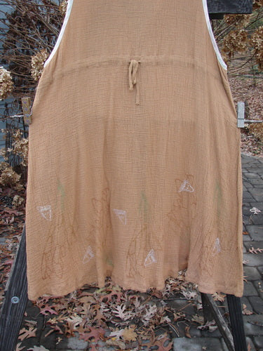 1998 Gauze Shell Vest Angel Wing Cork Size 2: A brown dress on a clothesline, close-up. Features include square shell buttons, hand-dyed silk ribbon edges, and an A-line shape.
