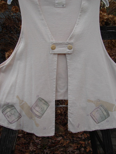 1999 The Tab Vest Baker Tea Dye Size 2: A white vest with a rolling pin and flour design. Features include a tab front, crop rear hemline, and shirt tail front. Double lined and made from organic cotton.