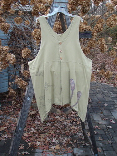 1998 Botanicals Aster Vest Long Stem Seed Size 2: A green vest with buttons on a wooden rack. Unique front and rear vents accented by wavy shell-like buttons. Can be worn forwards or back.