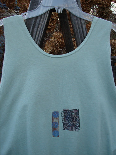1992 Workout Tank Elements Cucumber OSFA: A light blue tank top on a clothes rack, perfect for hot summer days. Slightly smaller size with a scooped neckline and deep arm openings. Features a unique swirly design.