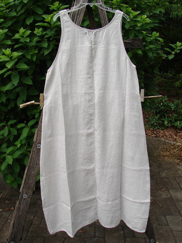 Barclay NWT Linen Sundress Spin Floral Garden Natural Fog Size 0 displayed outdoors, hanging elegantly on a clothesline and draped over a wooden ladder, showcasing its intricate pattern design.