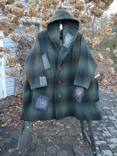 1995 Patched Hooded Autumn Jacket in Cottage Green Plaid, OSFA. A coat on a stand, featuring vintage buttons, a cozy double-lined hood, and deep side pockets. Rarely seen, this is a true winter treasure!