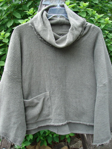 Barclay Sherpa Patched Wide Cowl Pocket Pullover Unpainted Sea Moss OSFA displayed on a hanger, showcasing its cozy fleece texture and unique hooded design, reflecting Bluefishfinder's vintage style.