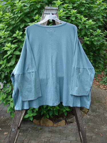 Barclay Two Pocket Mariposa Pullover Blue Sea OSFA displayed on a wooden rack, showcasing its unique design with dual pockets. A blend of style and comfort from Bluefishfinder.com’s vintage collection.