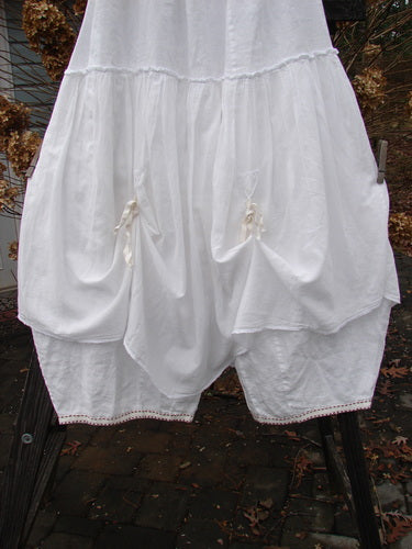 Image alt text: Barclay Hemstitch Embroidered Fusion Pant Skirt in White - A white pant skirt with exterior lacy seams, tie accents, and a cropped under pant. Features a billowy shape and stitched lower cuff accents. Size 2.
