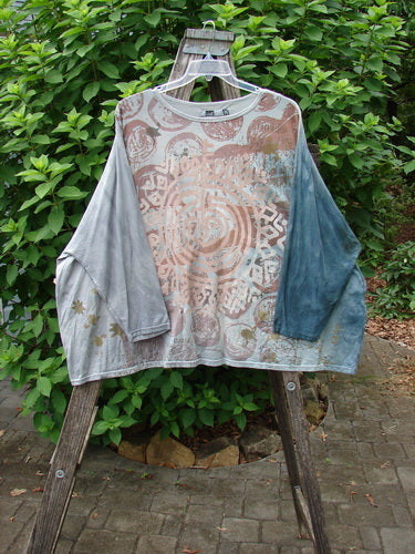 Barclay Dolman Sleeved Big Square Tunic Primitive Path Mottled Teal Gray OSFA displayed outdoors on a wooden pole, highlighting its intricate pattern and flowing fabric, embodying BlueFishFinder's vintage style.