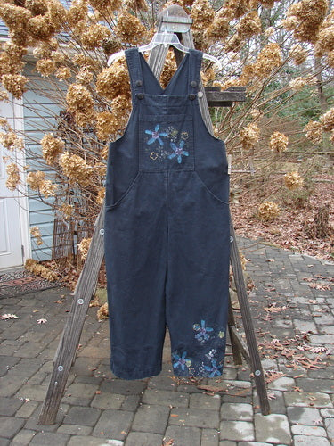 2000 Parachute Overall Jumper Floral Black Size 0: A blue overall with flowers, featuring a front bib pocket, adjustable shoulder straps, and wide swingy lowers.