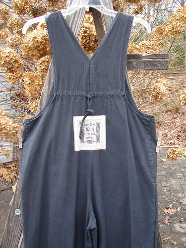 A close-up of a 2000 Parachute Overall Jumper in black. Features include a front bib pocket, side pockets, adjustable shoulder straps, and wide swingy lowers. Size 0.