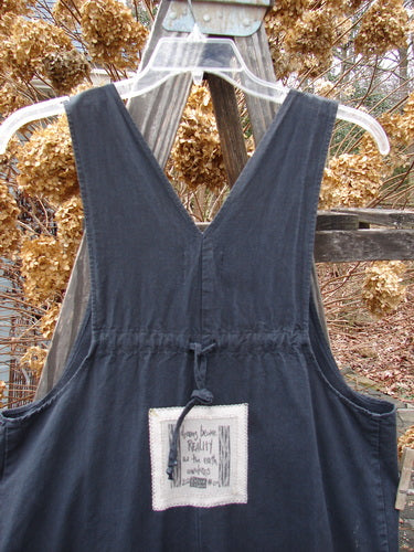 2000 Parachute Overall Jumper Floral Black Size 0: A black dress on a swinger with a tag close-up. Features oversized bib pocket, deep side pockets, adjustable shoulder straps, metal button side adjustments, wide swingy lowers, drawcord back, and floral theme paint.