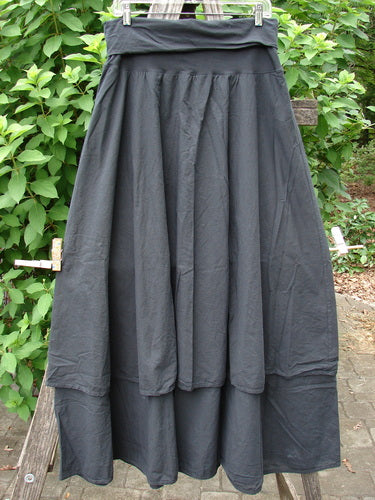 Barclay NWT Batiste Fold Over Stardust Two Tier Skirt Unpainted Black Raven Size 0 displayed elegantly on a wooden pole, showcasing its flowing layers and intricate design perfect for creative expression.