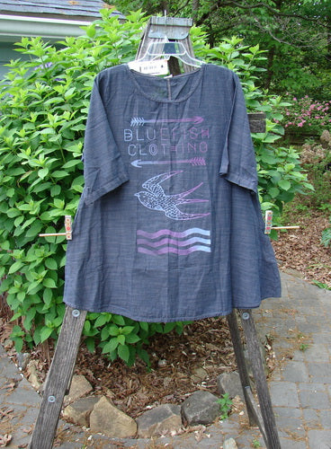 Barclay NWT Chambray Short Sleeved Promotional Top in dark denim striation, displayed on a rack. Features a rounded neckline, A-line shape, and promotional art from Bluefishfinder.com’s summer collection.