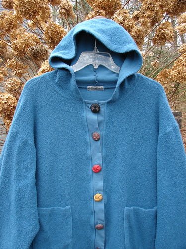 Barclay Celtic Moss Swing Hooded Jacket Unpainted Dusty Teal Size 2: A cozy blue jacket with buttons and a hood, made from soft and heavy Celtic Moss fabric. Features include an A-line shape, drop pockets, and oversized fancy buttons.
