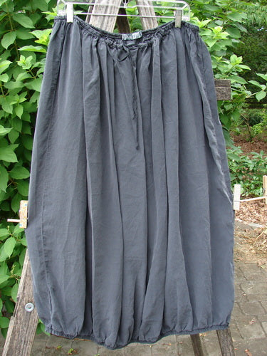 Barclay Silk Drawstring Bell Skirt Unpainted Raven OSFA draped on a wooden pole, showcasing its elegant, flowing design and craftsmanship, reflecting BlueFishFinder.com's commitment to unique vintage clothing resale.