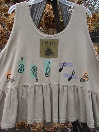 1992 Peplum Top Music Festival Wheat OSFA: A tan tank top with a graphic design of guitars. Baby doll style with a wide waist and a gathered bottom flounce. Perfect for layering!
