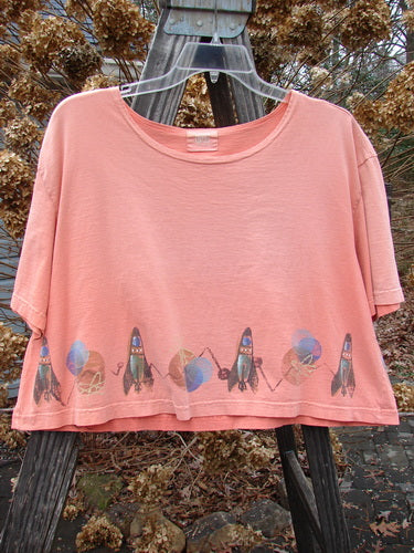 2000 Short Sleeved Crop Tee Rocket Coral Size 1: A pink shirt with rocket designs on it, featuring a wider neckline and a super wide crop box shape.