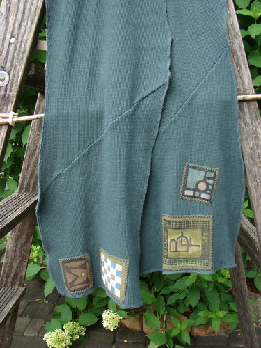 Barclay Thermal Patched Curvy Scarf Army Forest OSFA, draped on a wooden ladder, showcases a waffle texture and curly edges, featuring four distinct patchwork squares, embodying Bluefishfinder.com's vintage, creative essence.