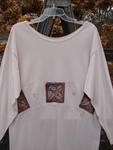 1995 Empire Dress Heart Leaf Champagne Size 1: A white shirt with brown designs, featuring a curved waist panel, rolled neck, and narrower sleeves.