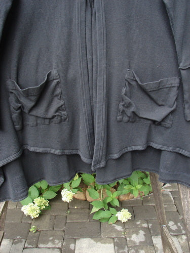 Barclay Patched Thermal Single Button Cardigan Tiny Square Black Size 0 draped on a chair, showcasing patch pockets and exterior curved stitchery, with a unique hemline and single wooden button closure.