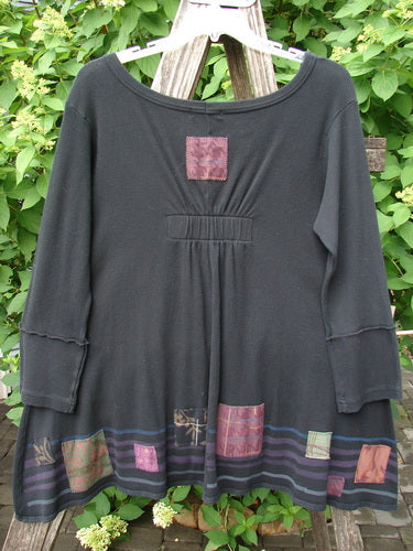 Barclay Patched Thermal Single Button Cardigan Tiny Square Black Size 0: A loose-fitting, long-sleeved tunic with a scooped neckline, flared hem, and appliquéd square patches, hanging on a wooden hanger.