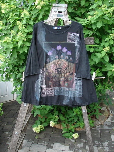 Barclay Three Quarter Sleeved Cafe Tee Floral Bloom Black Size 0, featuring intricate lotus blossom design on the front, displayed on a rustic wooden ladder, showcasing its loose fit and unique neckline.