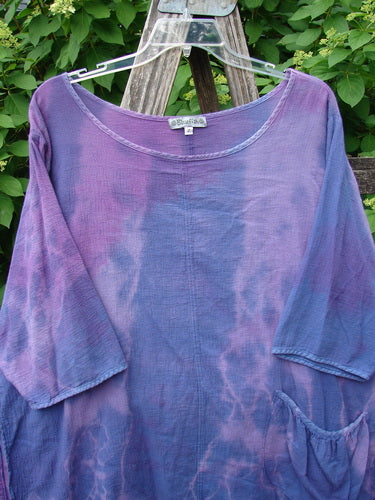 Barclay Gauze Round Bottom Tie Back Pocket Top Mottled Purple Dusk Size 2, featuring a scooped neckline, mid-length sleeves, and a side pocket, displayed on a hanger against a natural backdrop.