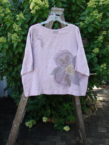 Barclay Linen Lantern Boxy Giant Blossom Hydrangea Size 1, featuring a stylized large flower, displayed on a rustic ladder against greenery, showcasing its square boxy shape and drop shoulders.