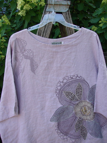 Barclay Linen Lantern Boxy Giant Blossom Hydrangea Size 1 features a floral print and drop shoulders, hanging on a clear plastic hanger over a rustic ladder, embodying BlueFishFinder's vintage style.