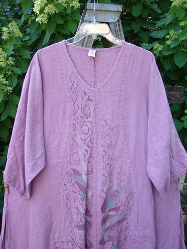 Barclay Linen High Vent Venetian Dress Center Leaf Peony Rose Size 1 features a muted lavender tunic with a V-neck, scroll-style cutouts, colored accents, and high side vents, highlighting its elegant drape.