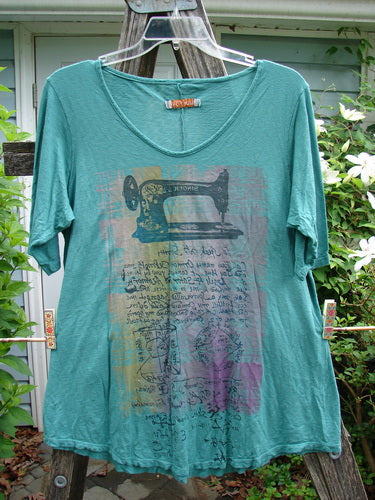 Barclay Slub Curve Bottom Tee Singer Seamstress Spearmint Size 1 features a rounded neckline, short sleeves, and A-line shape with a varied hemline, showcasing artistic seamstress-themed detailing.