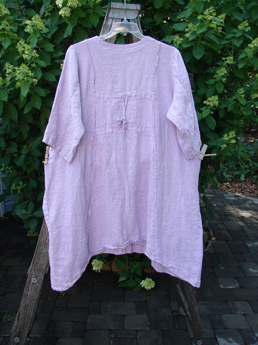 Barclay Linen Double Tie Back Jacket Single Garden Row Pink Cloud Size 1 displayed outdoors on a wooden ladder, features elbow-length sleeves and a loose, flowing design with a deep V-neckline.