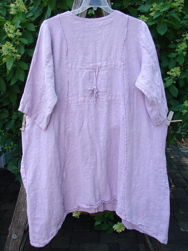 Barclay Linen Double Tie Back Jacket Single Garden Row Pink Cloud Size 1, featuring a loose fit, 3/4 sleeves, deep V-neckline, and draw-tie waist, displayed against lush foliage.