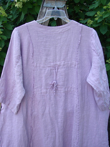 Barclay Linen Double Tie Back Jacket Single Garden Row Pink Cloud Size 1 displayed against greenery, showcasing its loose fit, V neckline, and three-quarter sleeves with a back waist tie.