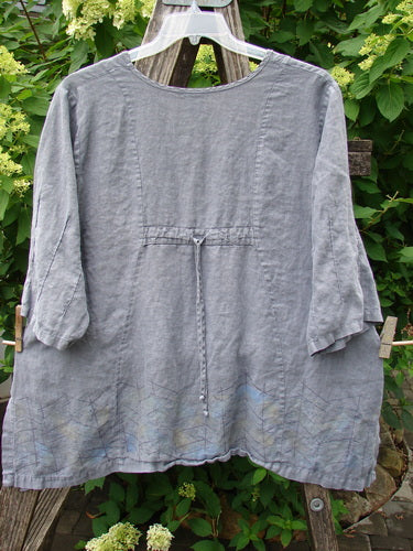 Barclay Linen Pinch Sleeve Curve Tie Back Top Border Twig Grey Size 1, showcasing a relaxed fit with subtle detailing, draped on a trellis amidst lush greenery, embodying BlueFishFinder's vintage, expressive style.