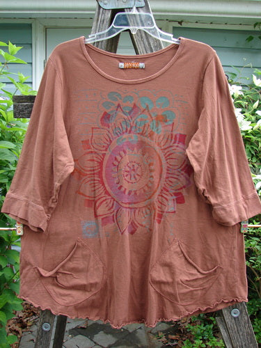 Barclay Banded Artist Pocket Top Sunflower Rust Size 1, featuring a rounded neckline, A-line shape, double diagonal pockets, three-quarter banded sleeves, giant sunflower theme, and rounded hemline with curly edges.
