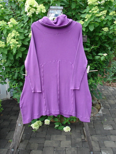 Barclay Thermal Cowl Collar Vertical Empire Pocket Dress Unpainted Magenta Size 1: A loose-fitting, long-sleeved tunic with a draped neckline, displayed outdoors against lush greenery, embodying Bluefishfinder.com's vintage and creative style.