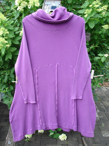 The Barclay Thermal Cowl Collar Vertical Empire Pocket Dress in Unpainted Magenta Size 1 hangs outdoors, showcasing its loose fit and wide cowl neck, set against lush greenery.