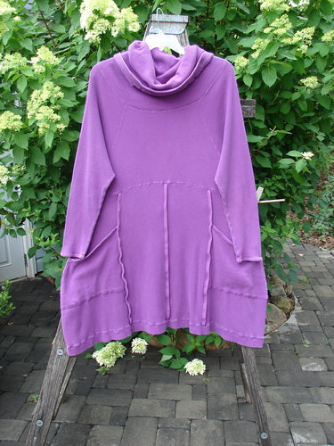 Barclay Thermal Cowl Collar Vertical Empire Pocket Dress Unpainted Magenta Size 1: A long-sleeved tunic with exposed seams and side pockets, elegantly displayed on a wooden ladder amidst lush greenery.