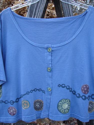 1993 Travel Top with Pinwheel Design, Size 2: A cropped periwinkle cotton shirt featuring a deep scoop neckline and ceramic glazed buttons.