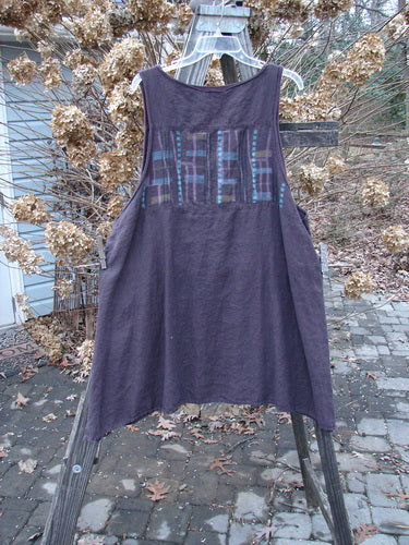 Barclay Linen Cross Over Pinafore Top Plaid Dark Plum Size 2: A V-neck dress with criss-cross ruffle, sectional panels, and side vents.