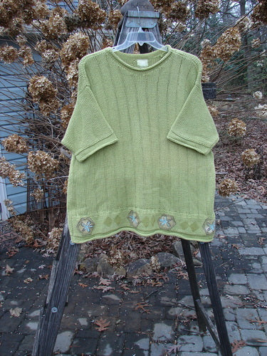 1999 Spring Pullover Tunic Sweater Kiwi Size 2: A green sweater with varied textures and knits, featuring an A-line shape, drop shoulders, and rolled neck sleeves and hemline.